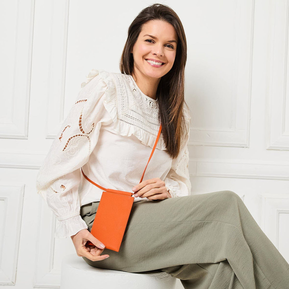 Image of a Model displaying the Image of a Model displaying the Orange Leather Phone Pouch for Women by Elie Beaumont